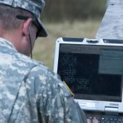 Officer reviewing laptop screen on field